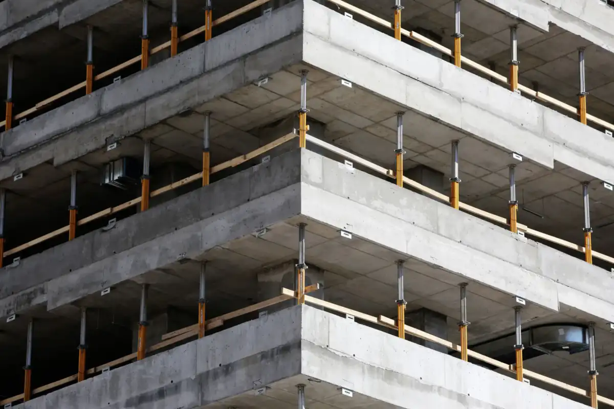 A multi-storey cast concrete building frame under construction, with the floor slabs and structural columns exposed before cladding.