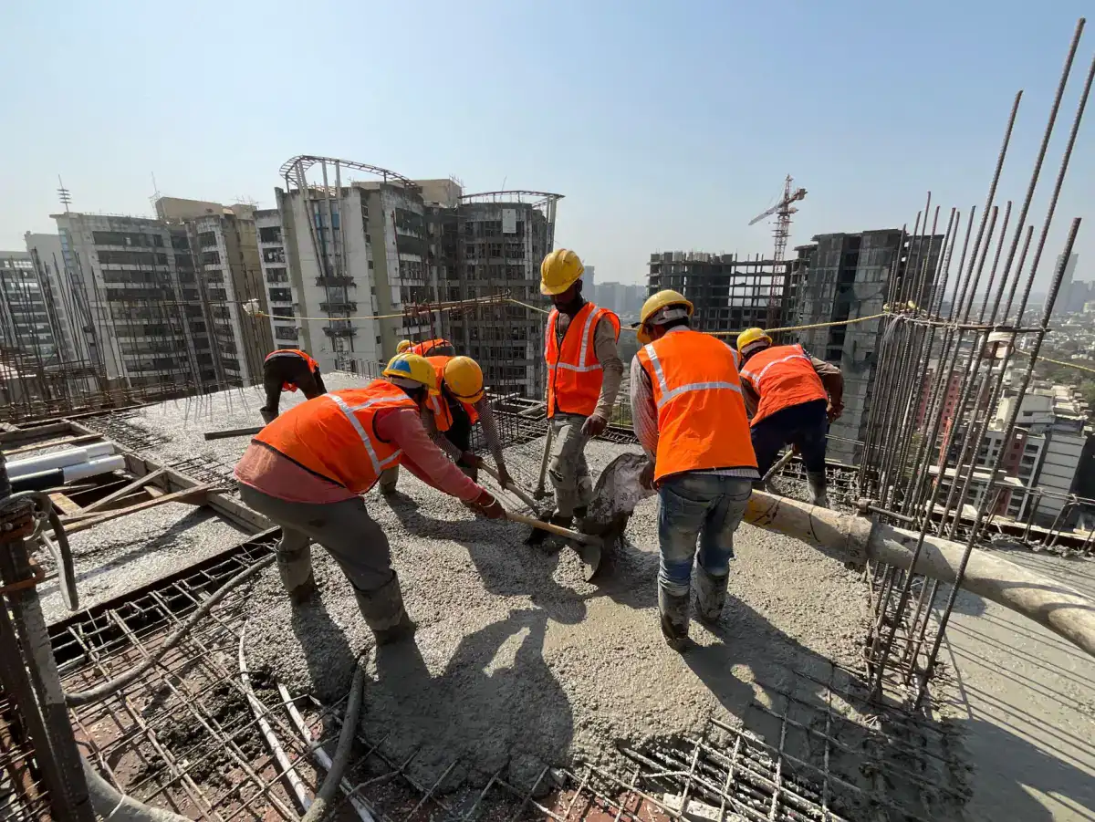 A crew in hard hats and high-visibility clothing placing and working fresh concrete across a reinforced deck, with reinforcing bar projecting around them.
