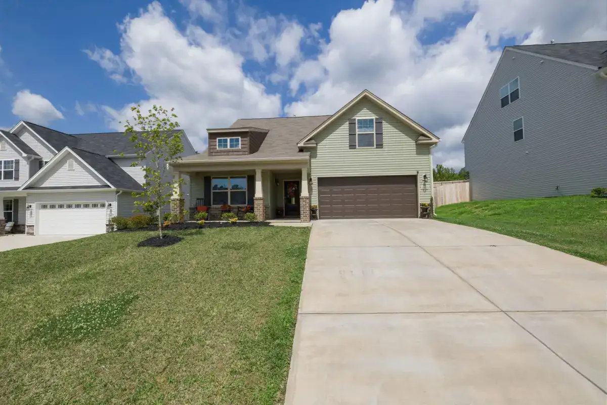 A clean concrete driveway running from the street up to an attached two-car garage, showing the wide apron and the transition where the drive meets the garage slab.