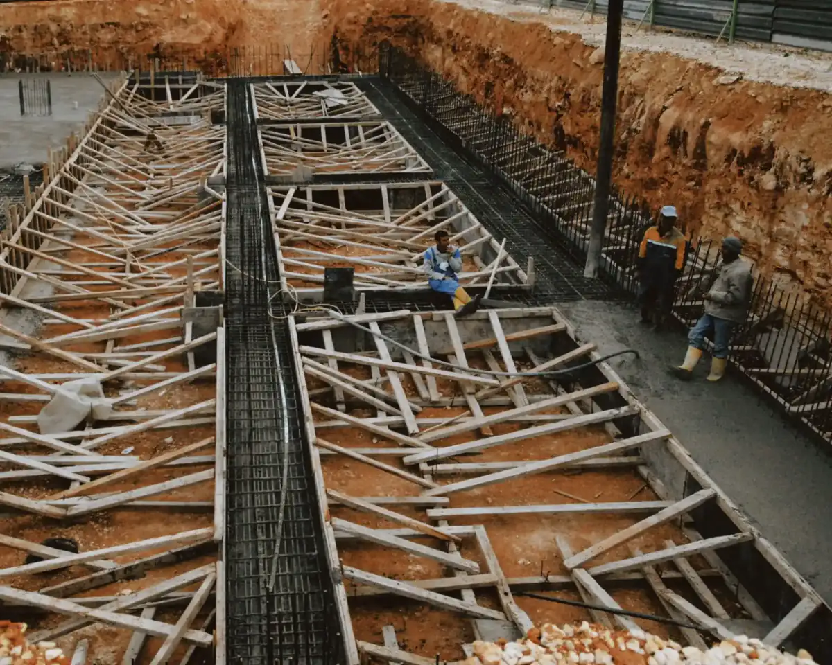 An excavated foundation trench with timber formwork braced along its length and reinforcing steel set in place, ready for concrete.