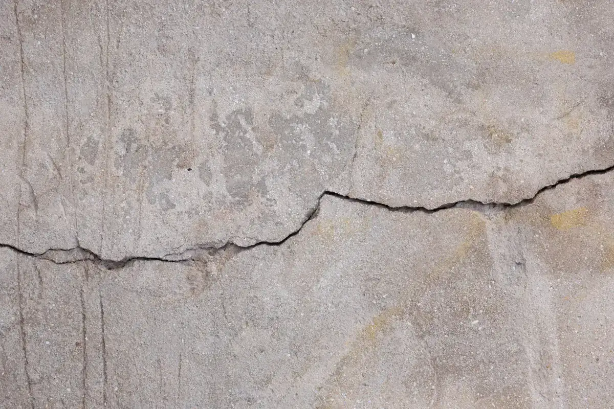 A wide crack running through a weathered concrete surface, the kind of full-depth failure that puts a slab past repairing.