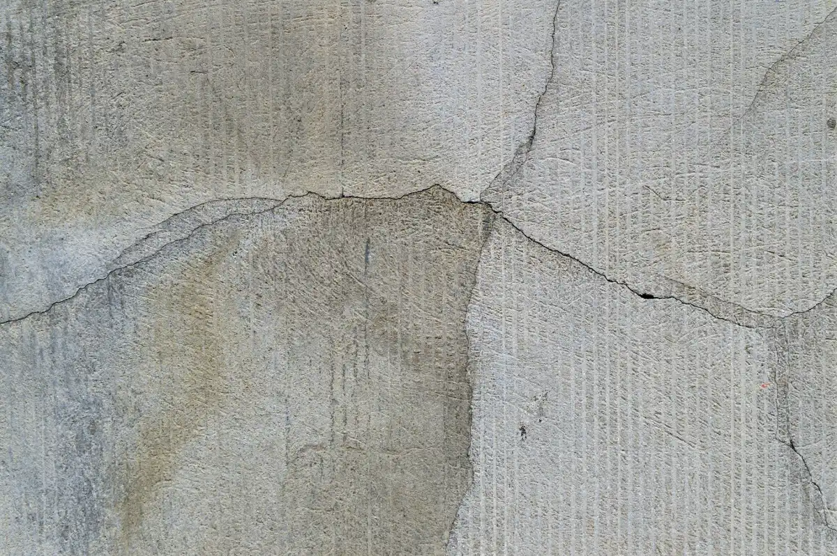 A crack running across a pale concrete surface, branching as it travels, with the surrounding slab still sound and intact.