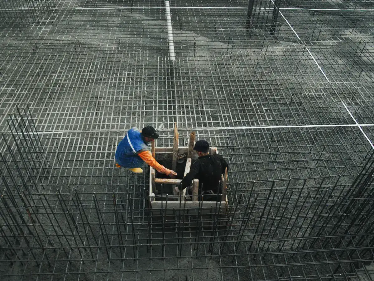 A wide mat of tied reinforcing bar laid out over a prepared subgrade, with a formed blockout box set into the middle of the grid.