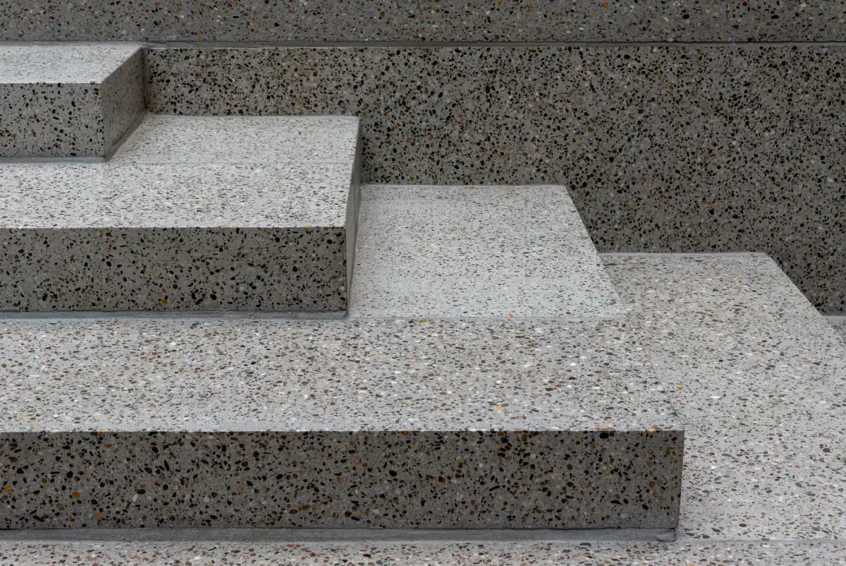 A wide concrete step and landing arrangement in exposed aggregate, showing how a low riser and a broad tread are formed where a flight meets a level surface.